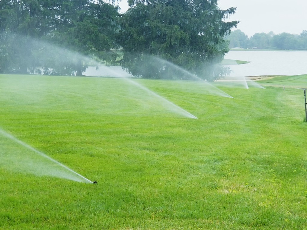 a green lawn with sprinklers turned on